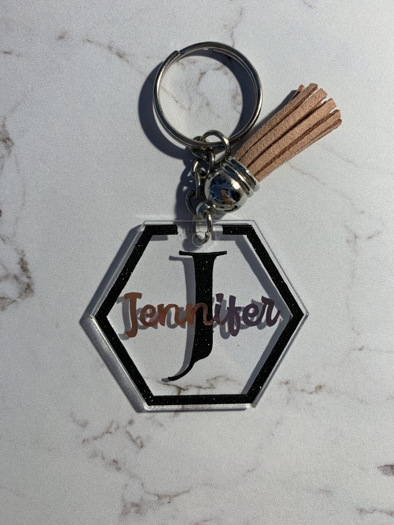 Hexagon keyring with name, featuring an outline and initial in shimmer black vinyl and name in rose gold. Finished with a tassel