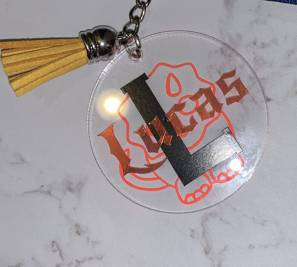 Rucksack keyring for a child, custom made to specific request. Has a dinosaur outline on the back in copper holographic vinyl and black vinyl