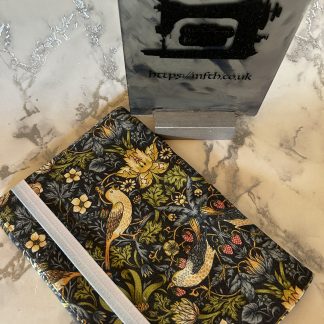 Book Cover made from several layers of fabric with an elasticated band to hold it together at the edge. The print is Navy with yellow bird and flowers in the William Morris Print
